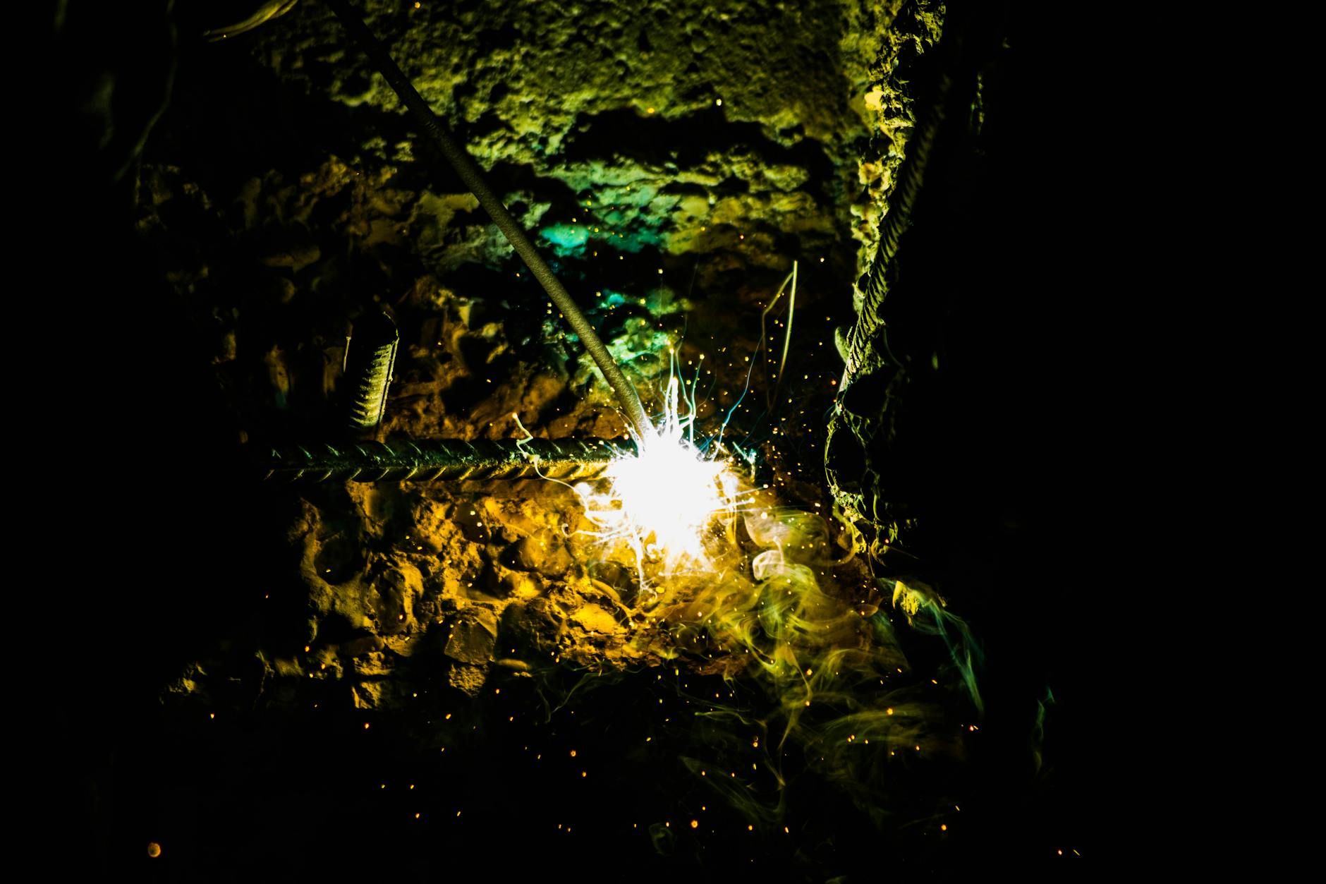 Dramatic capture of welding sparks illuminating a dark construction site with vivid light and texture.