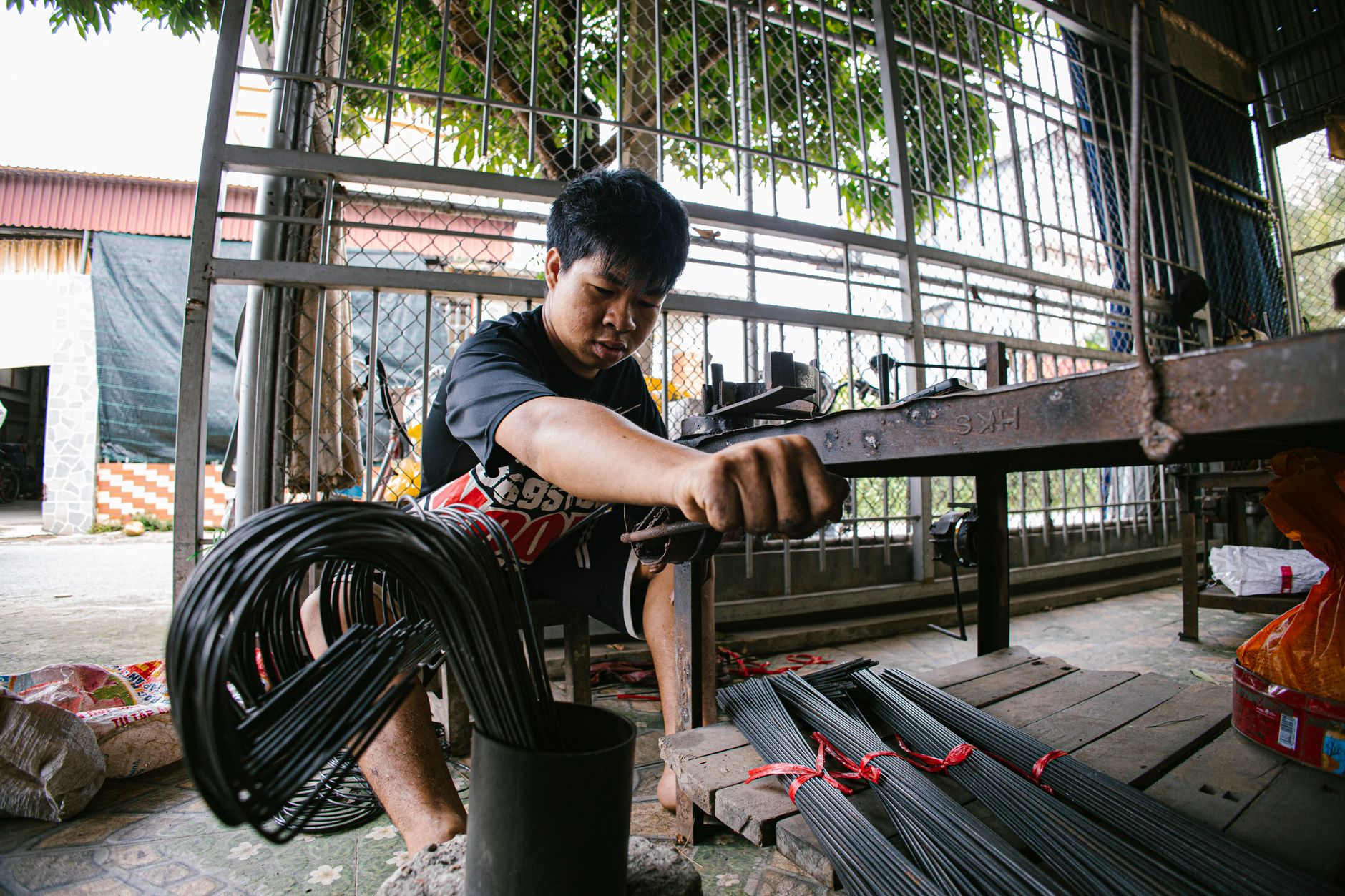 Individual handling metal wire in an indoor workshop with industrial equipment.