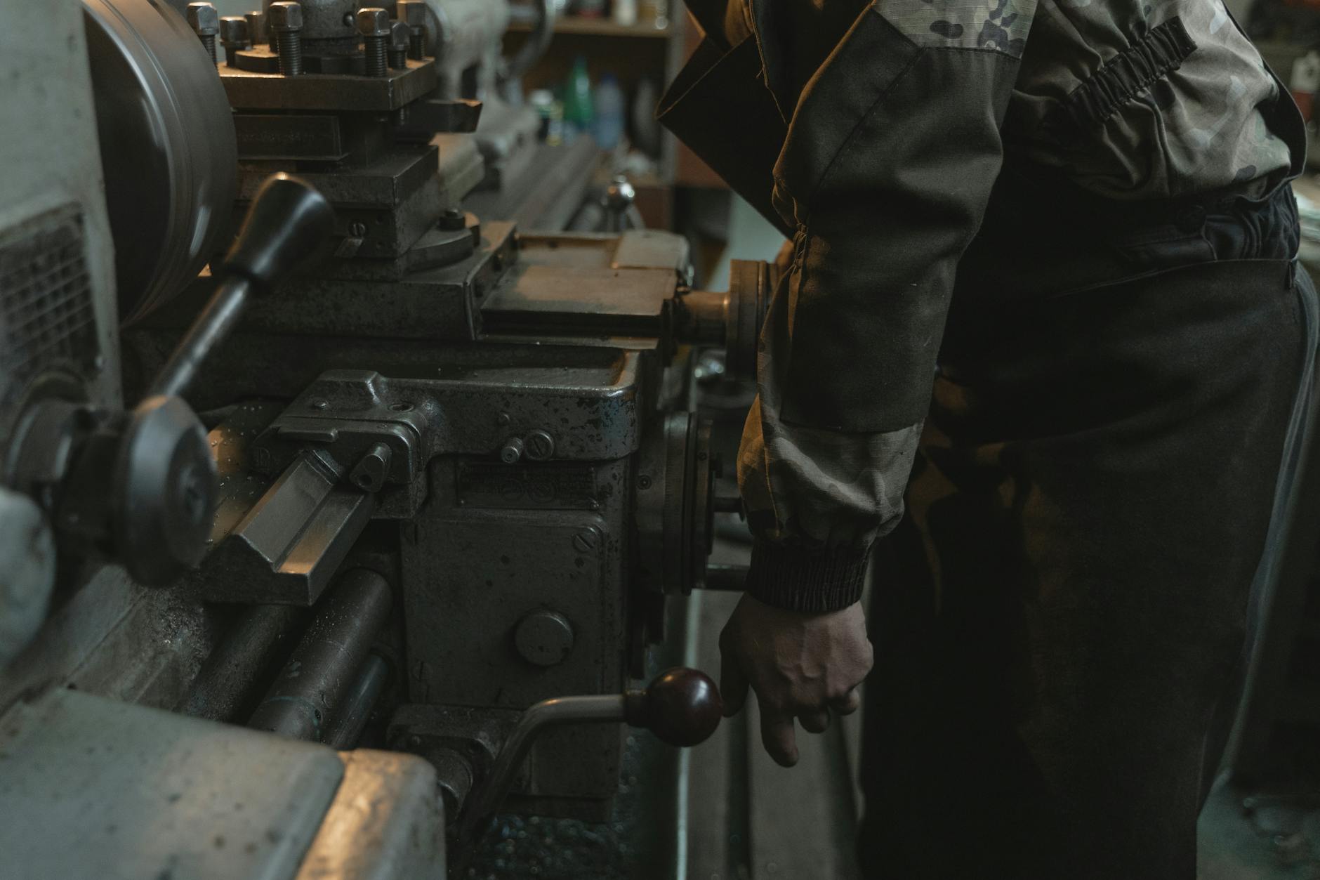 Close-up of a craftsman working on a lathe machine in an indoor workshop setting.