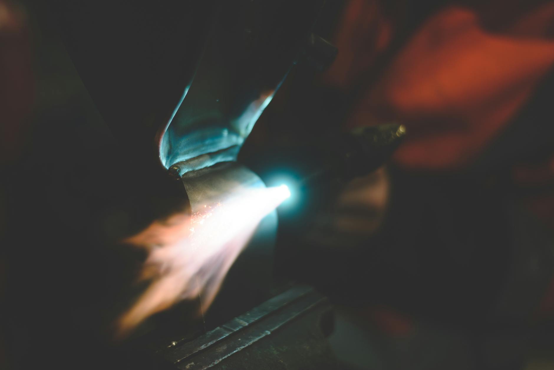 Metalwork with a blow torch creating a bright flame in a workshop setting.